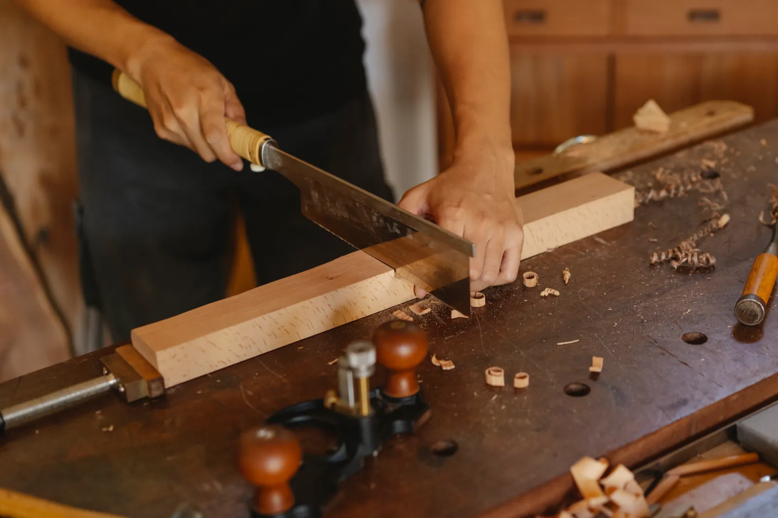 Tischler sägt ein Holzbrett auf der Hobelbank zu, Maßanfertigung von Treppenstufen in der Werkstatt