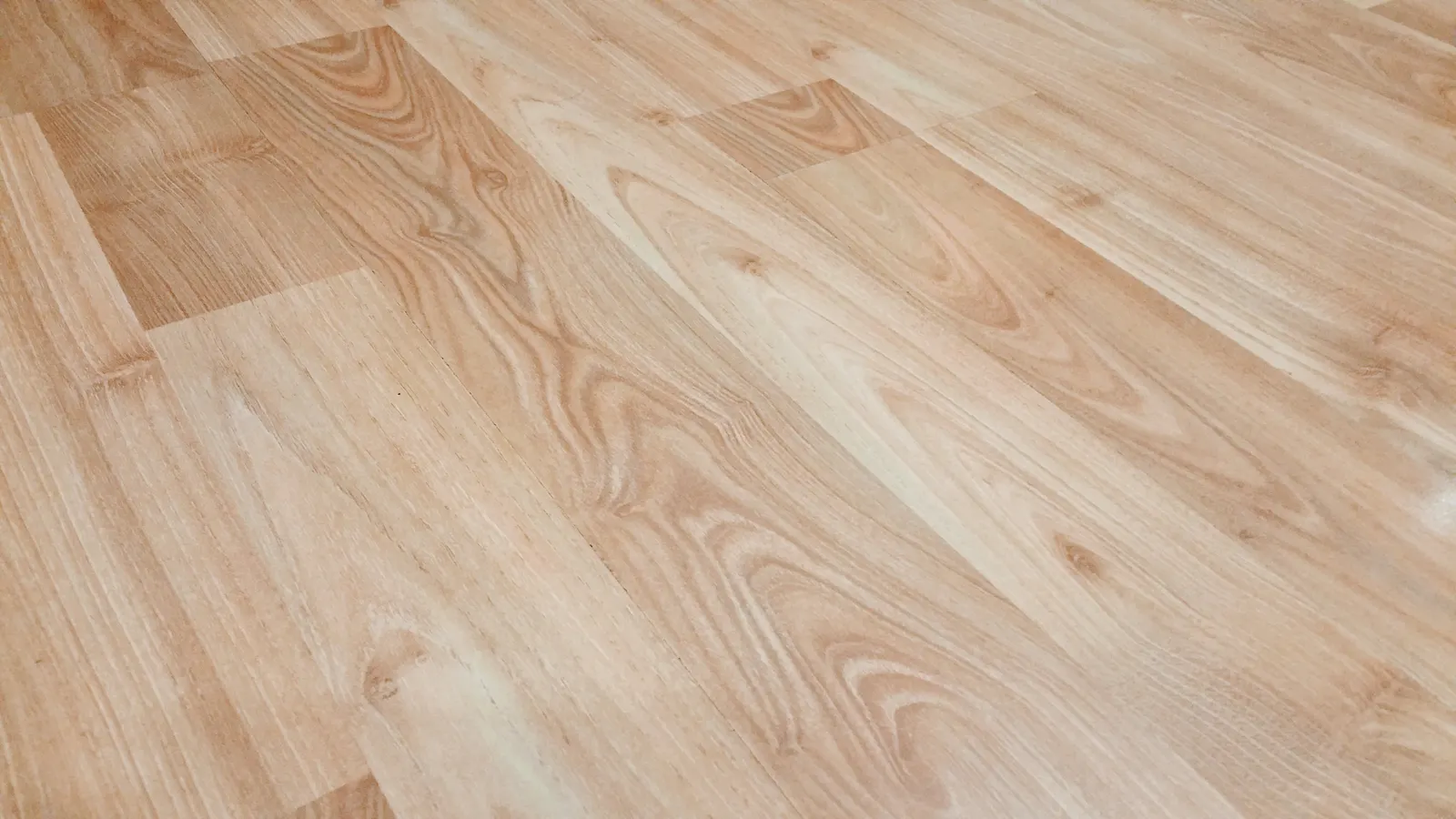 Nahaufnahme eines hellen Dielenbodens in Holzoptik mit sichtbaren Stoßkanten und feiner Holzstruktur